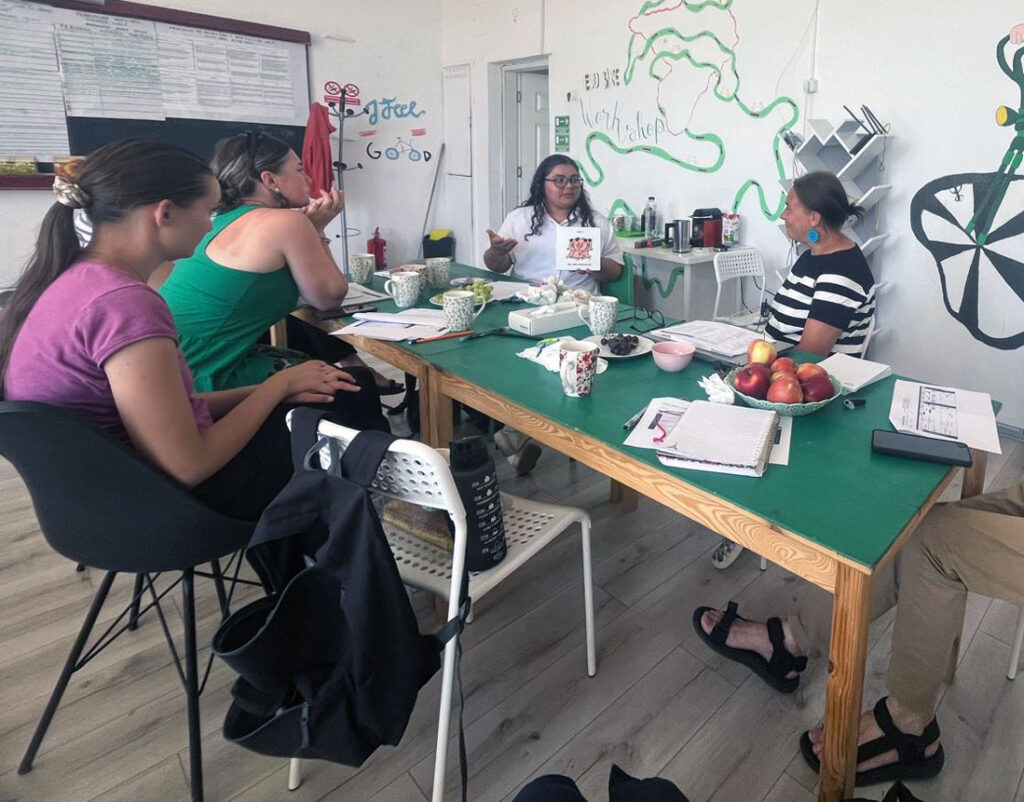 A group of five people sit around a table talking.